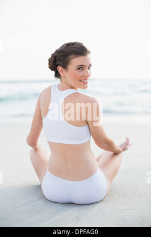 Glücklich schlank braun behaart Modell in weiße Sportbekleidung im Lotussitz meditieren Stockfoto