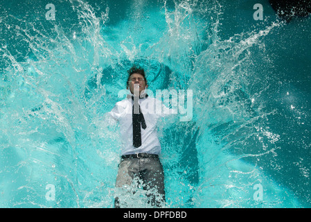 Junger Mann in der Kleidung ins Schwimmbad fallen Stockfoto