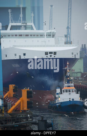 Stralsund, Deutschland. 14. Januar 2014. Das letzte neue Schiff in P S-Werft Volkswerft Stralsund, einem Spezialtransporter 'Roll on - Roll-off Cargo' mit der Fabriknummer 501 für die dänische Reederei DFDS, der das Schiffshebewerk von Schlepp Boote vor der Schiffbauhalle der insolventen Shopyard P S-Werft Volkswerft in Stralsund, Deutschland, 14. Januar 2014 gezogen wird gebaut werden. Dänische Reederei DFDS a/s hat zwei Transportschiffe in Stralsund bestellt. Foto: STEFAN SAUER/Dpa/Alamy Live News Stockfoto