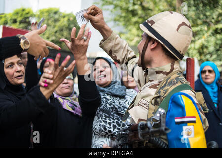 Kairo, Ägypten. 14. Januar 2014. Ein Soldat gibt Tickets für Anhänger der ägyptischen Armee und Armee Chef General Abdel Fattah al-Sisi vor einem Wahllokal in Kairo, Ägypten, 14. Januar 2014 als "Vielen Dank für die Zusammenarbeit mit uns" geschrieben. Ägypter begann ihrer Stimmabgabe am Dienstag über das Land neuen Verfassungsentwurf, die weithin gilt als ein Meilenstein beim politischen Übergang Ägyptens nach islamistischen Präsident Mohamed Morsi im Juli letzten Jahres gestürzt wurde. Bildnachweis: Pan-Chaoyue/Xinhua/Alamy Live-Nachrichten Stockfoto