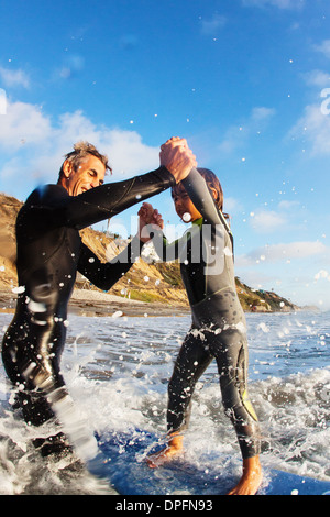 Vater und Tochter springen im Meer, Encinitas, Kalifornien, USA Stockfoto