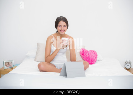 Erfreut junge braunen Haaren Modell in weißen Schlafanzug genießen einen Kaffee Stockfoto