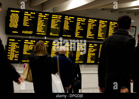 Pendler auf der Abfahrtstafel betrachten eine am Bahnhof Birmingham New Street, Birmingham Stockfoto