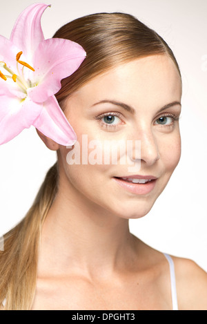 Junge Frau trägt Lily in Haar, portraitwearing Stockfoto