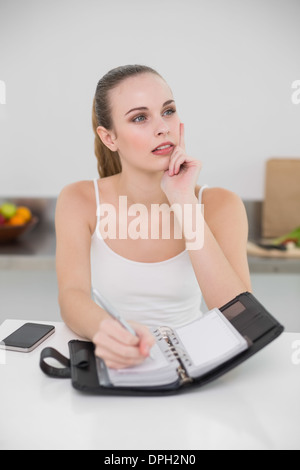 Nachdenkliche junge Frau in einem Planer schreiben Stockfoto