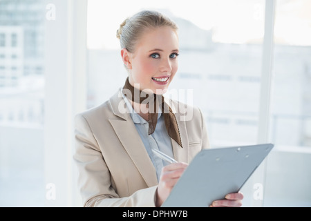Blonde lächelnde Geschäftsfrau Holding Zwischenablage Stockfoto