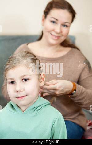 Mutter überfallen die Haare ihres Kindes sitzt im Wohnraum Stockfoto