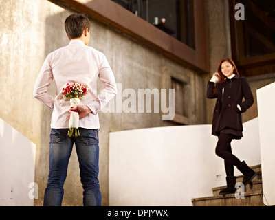 junger Mann wartet Freundin mit Blumen Stockfoto