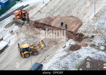 Arbeiten Sie mit der Überarbeitung der Heizung auf der anderen Straßenseite. Auffüllen der Gräben mit Sand von Traktor. Russland Stockfoto