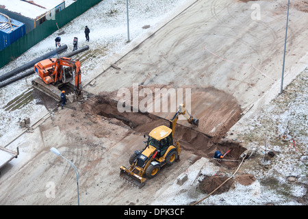 Arbeiten Sie mit der Überarbeitung der Heizung auf der anderen Straßenseite. Auffüllen der Gräben mit Sand von Traktor. Russland Stockfoto