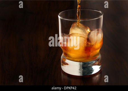 Whisky in ein Glas mit Eis drin auf einem dunklen Hintergrund aus Holz Stockfoto