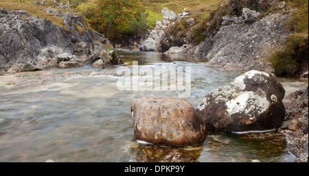 Gebirgsbach in Schottland aufgenommen mit Langzeitbelichtung und Schwerpunkt auf den Felsen im Vordergrund. Stockfoto