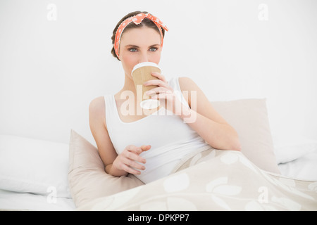 Frau trinkt einen Kaffee in ihrem Bett liegend Stockfoto
