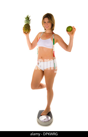 Eine Frau auf eine Waage mit Früchten in ihren Händen Stockfoto