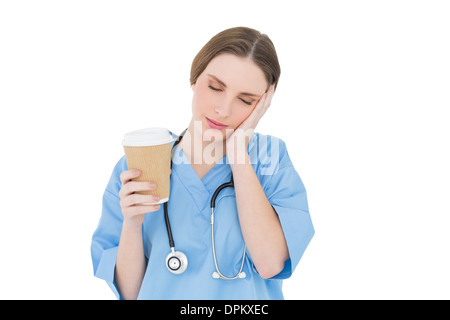 Ärztin hält eine Kaffeetasse und heben ihre Hand, um ihr Gesicht mit geschlossenen Augen Stockfoto