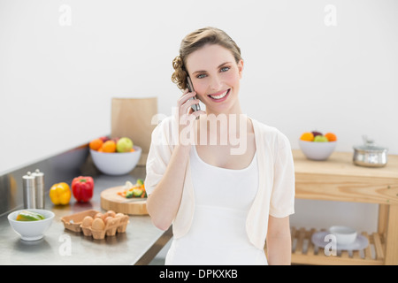Fröhliche junge Frau telefonieren mit ihrem Smartphone stehen in Küche Stockfoto