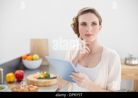 Junge nachdenkliche Frau in Küche durchlöchern ihr tablet Stockfoto