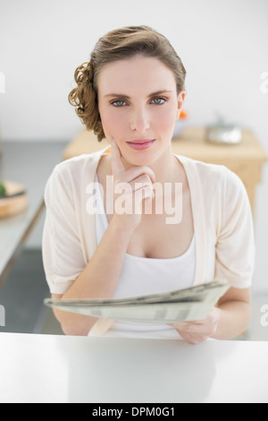 Wunderschöne denken Frau sitzt in ihrer Küche hält Zeitung Stockfoto