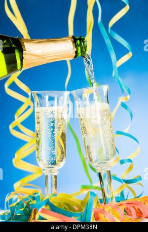 Eine Flasche und zwei Glas Sekt, Luftschlangen und blauem Hintergrund Stockfoto