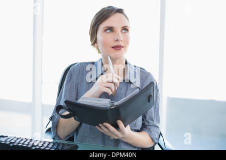 Denken Geschäftsfrau hält ihr Tagebuch beim Sitzen an ihrem Schreibtisch Stockfoto