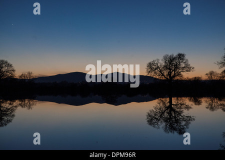 Die Sonne geht hinter den Malvern Hills in Worcester, spiegelt sich in überfluteten Ackerland Stockfoto