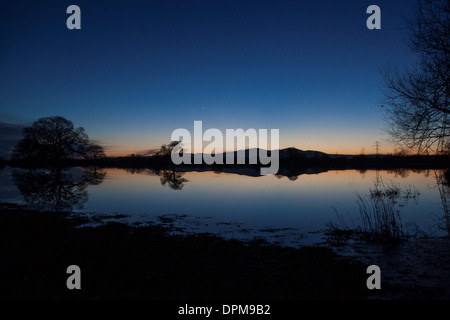 Die Sonne geht hinter den Malvern Hills in Worcester, spiegelt sich in überfluteten Ackerland Stockfoto