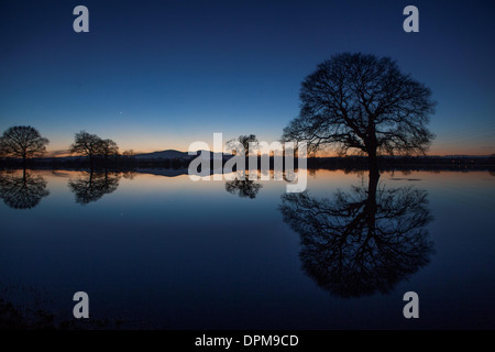 Die Sonne geht hinter den Malvern Hills in Worcester, spiegelt sich in überfluteten Ackerland Stockfoto