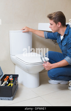 Gut aussehend Klempner mit Toolbox Toilette Wiedergutmachung zu tun Stockfoto