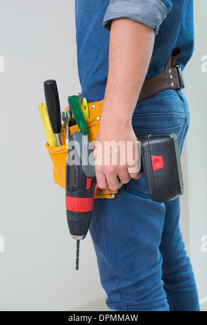 Seitenansicht Mittelteil ein Handwerker mit Bohrer und Werkzeuggürtel Stockfoto