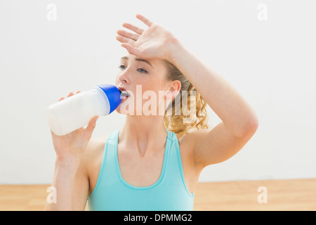 Erschöpft, schlanke blonde sitzen auf Boden trinken aus Sport-Flasche Stockfoto