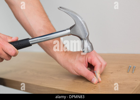 Händen Hämmern Nagel in Holzbank Stockfoto