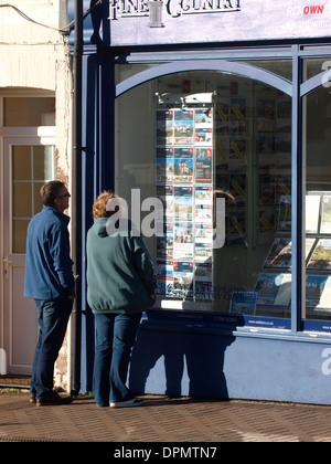 Mittleren gealterten paar auf der Suche in Immobilienmakler Fenster, Bude, Cornwall, Großbritannien Stockfoto