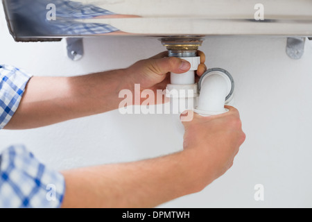 Klempner Hände und Waschbecken Abfluss im Badezimmer Stockfoto