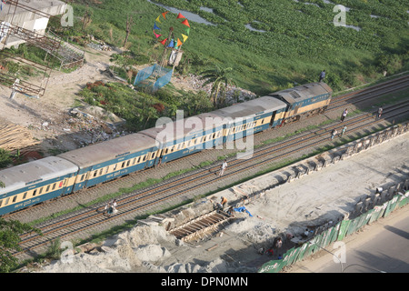 Einer der vielen regelmäßig Züge auf der Durchreise Dhaka, Bangladesh. Beachten Sie die Menschen entlang der Strecke und die Menschen auf dem Dach Stockfoto