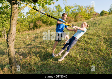 Eine Frau benutzt Aussetzung Ringe auf einer Wiese Stockfoto