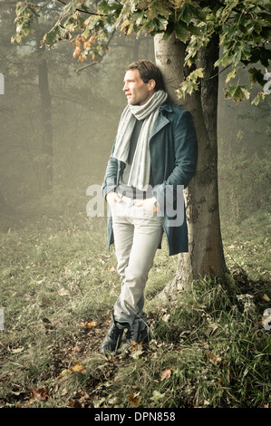 Mann an einen Baum gelehnt, im Herbst Stockfoto