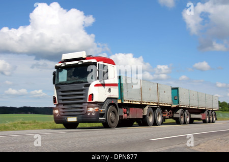 Volle Anhänger lange Transport-LKW auf der Straße, die Fahrt durch die Landschaft im Sommer, Bewegungsunschärfe auf den Hintergrund. Stockfoto