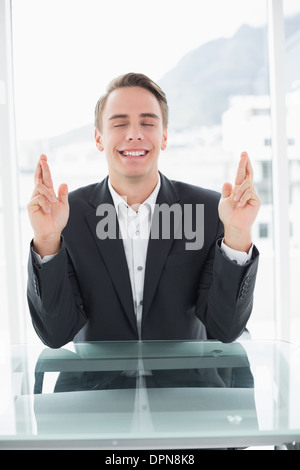 Lächelnde Geschäftsmann mit Finger kreuzten sich im Büro-Schreibtisch Stockfoto