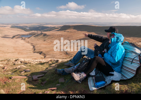 Wanderer ausruhen während Pen Y Fan, South Wales höchsten Punkt, mit Blick auf die Neuadd Reservoir zu klettern. Stockfoto