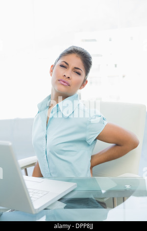 Junge Geschäftsfrau leiden unter Rückenschmerzen im Büro Stockfoto