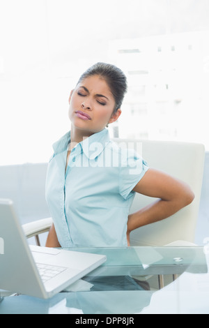 Junge Geschäftsfrau leiden unter Rückenschmerzen im Büro Stockfoto