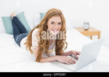 Lächelnde lässig Blond mit Laptop im Bett Stockfoto