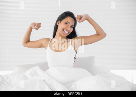 Schöne Frau sitzt auf ihrem Bett ausstrecken Stockfoto