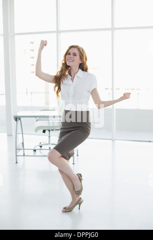 Fröhliche elegante Geschäftsfrau im Büro jubelt Stockfoto