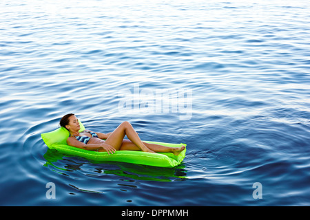 Mädchen auf einer schwimmenden Lilo im Wasser Stockfoto