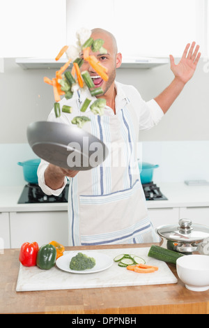 Mann warf Gemüse in der Luft in der Küche Stockfoto