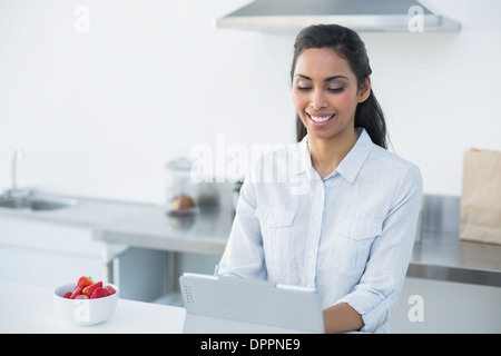 Schöne Frau, die arbeitet auf ihrem Tablet ansehen in ihrer Küche Stockfoto