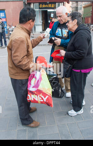 Peking, China. 26. Oktober 2006. Ein amerikanischer Tourist paar kaufen eine Baseball-Cap aus einem Straßenhändler, hält einen Dollarschein in Peking, Hauptstadt der Republik China. © Arnold Drapkin/ZUMAPRESS.com/Alamy Live-Nachrichten Stockfoto