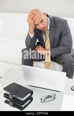 Besorgt Geschäftsmann mit Laptop mit Kopf in Hand zu Hause Stockfoto