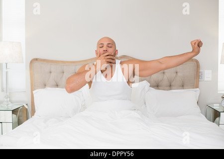 Mann im Bett aufwachen und streckte die Arme Stockfoto